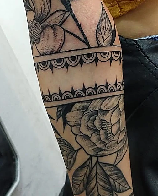 Flores en línea y puntillismo con bandas ornamentales a lo largo del antebrazo